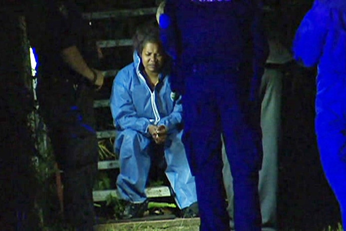 Liddel Ramsey, 24, sits in a hazmat suit in police custody at a home at Annerley.