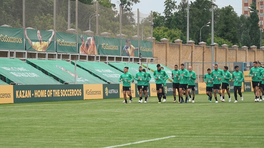 The Socceroos run on grass in a stadium with large banners saying #GoSocceroos, and Kazan - Home of the Socceroos