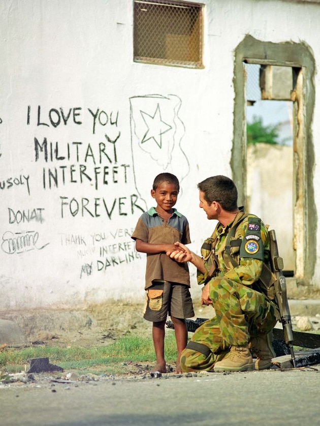 An Australian soldier talks to a local boy during deployment in Timor-Leste.