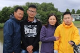 A mother and father standing with two teenage sons.