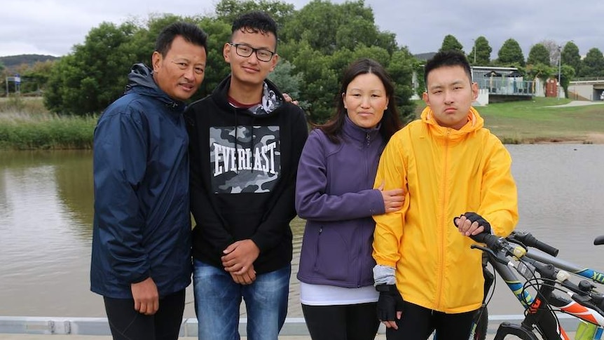 A mother and father standing with two teenage sons.