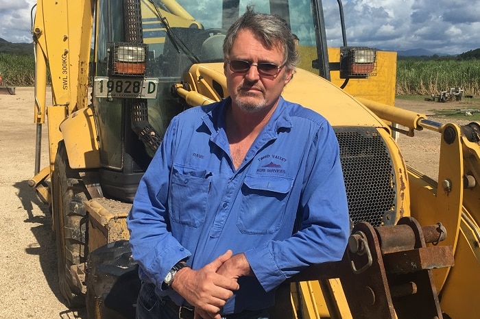 Cane grower David Bartlett with the heavy earth moving machinery he is hoping to repair after it was inundated by flood water.