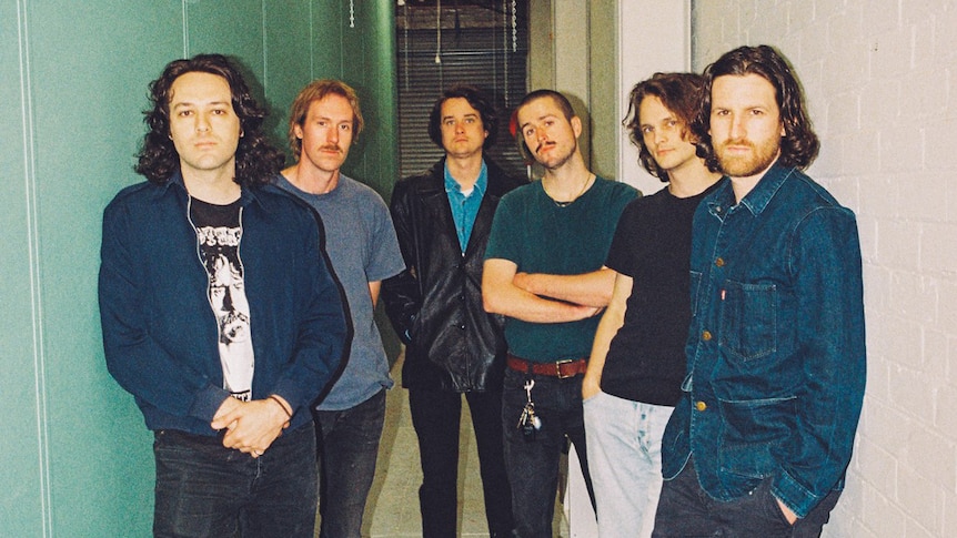 The six members of King Gizzard and the Lizard Wizard stand in a hallway