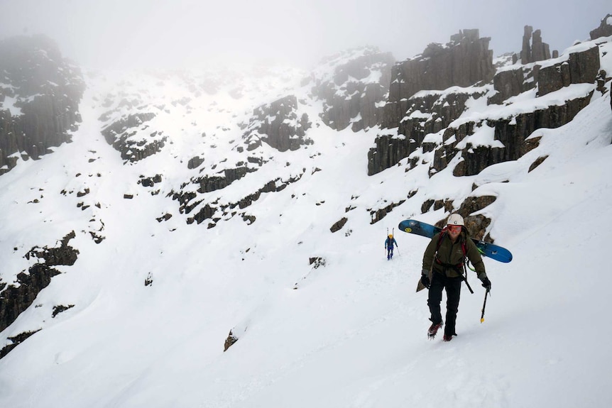 A snowboarder ascends Cradle Mountain
