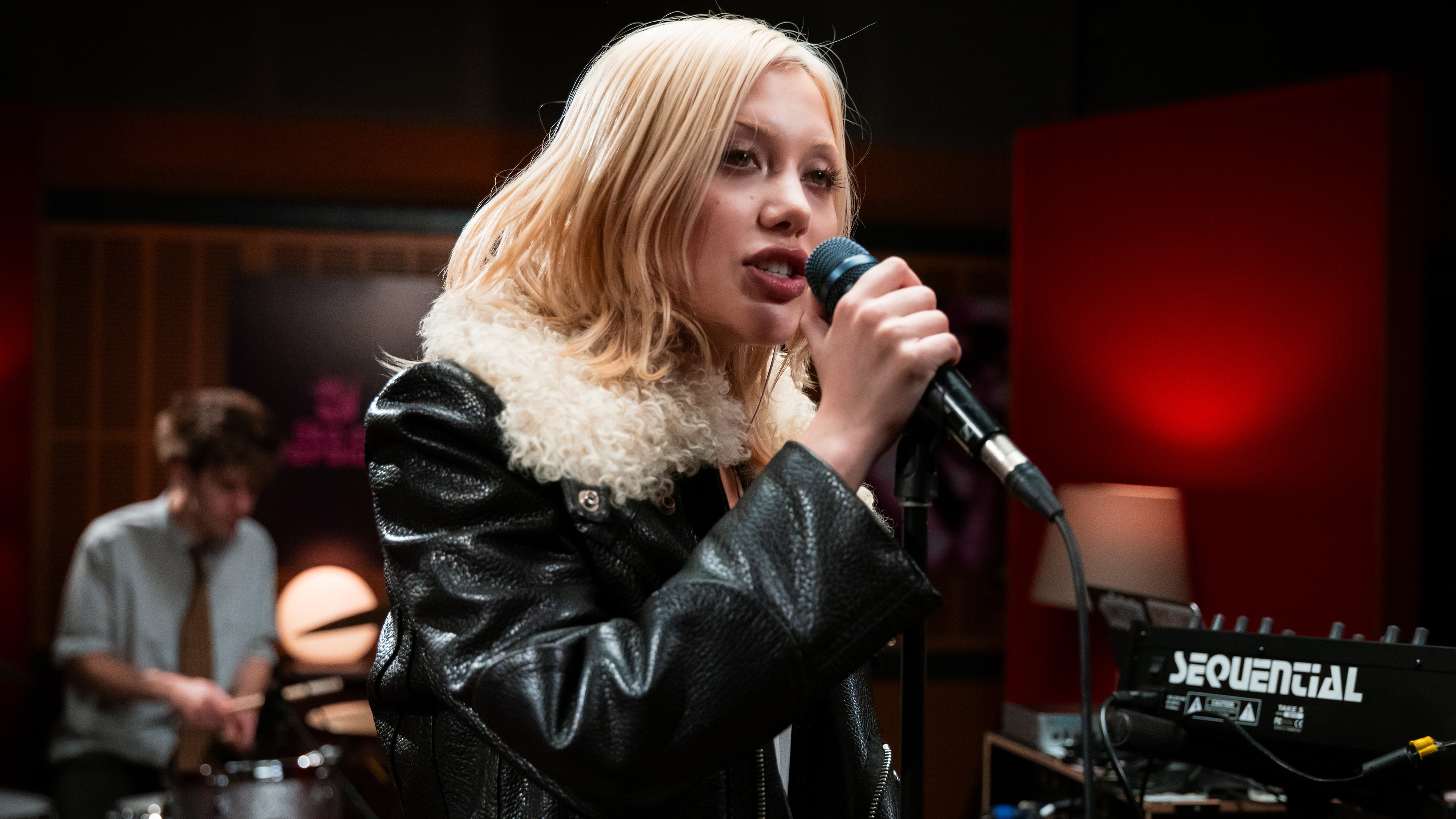daine singing into a microphone in a dimly lit studio