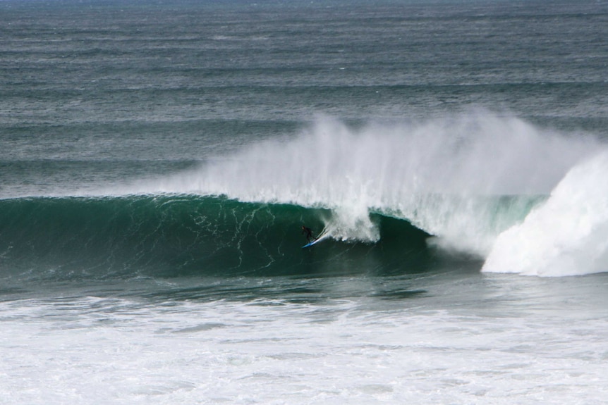 surfer on a large wave as it starts to break over his head