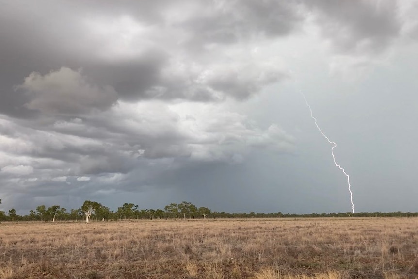 lighting hitting the ground with a plain in the foreground and stormy clouds above.
