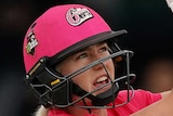 A Sydney Sixers WBBL batter wearing a helmet and holding a bat hits out to the leg side against Hobart Hurricanes.