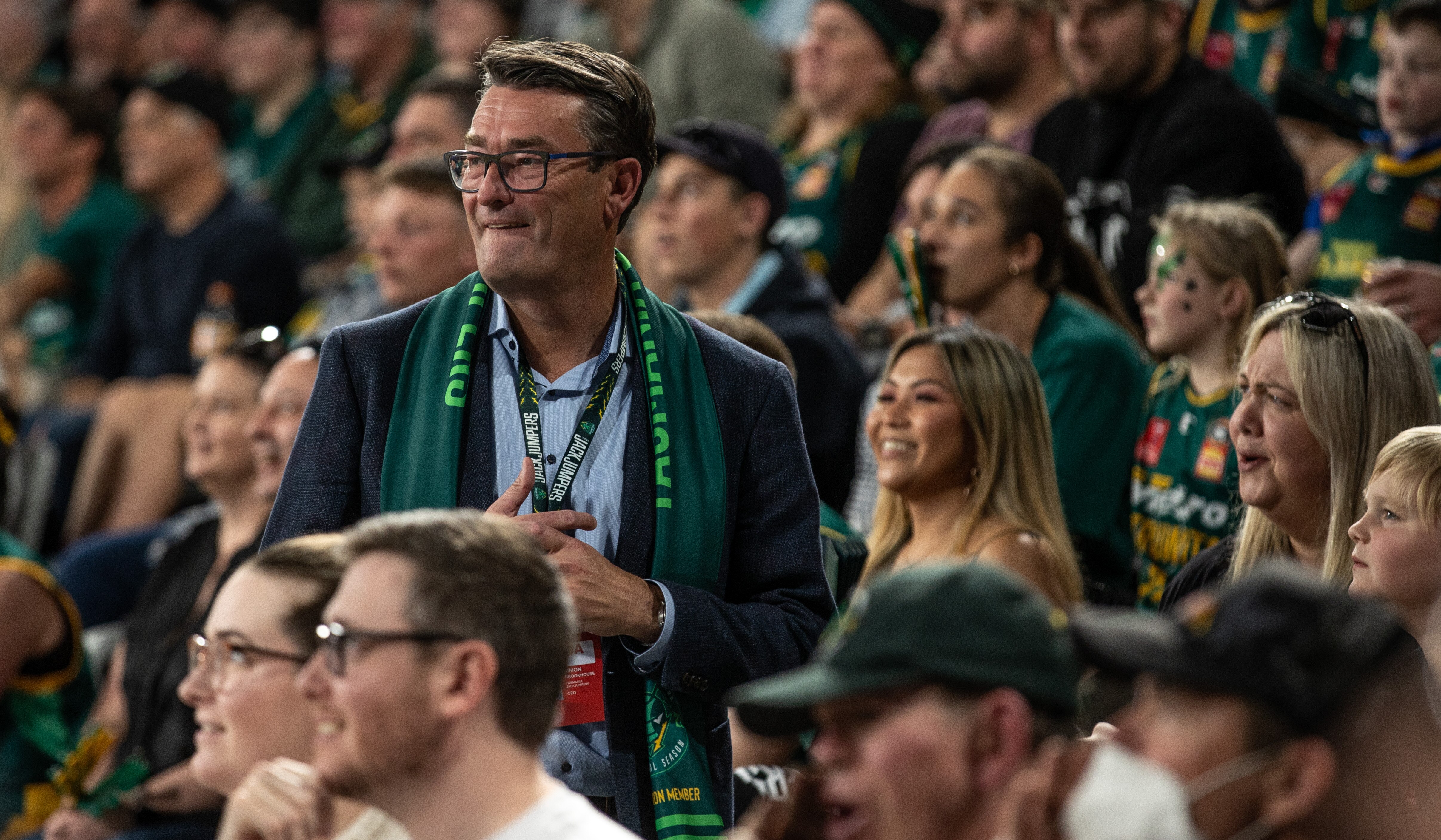 Middle aged man wearing a Jack Jumpers basketball team scarf watches a game 