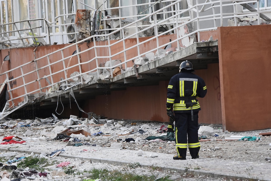 A firefighter stands next to an apartment building damaged by Russian shelling.