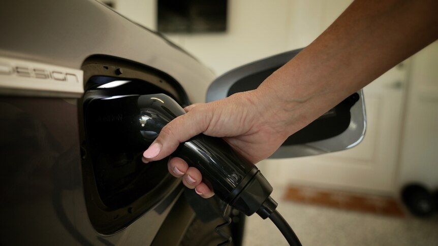 a close up of a woman charging an EV