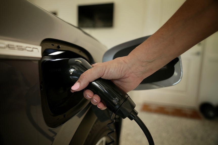 a close up of a woman charging an EV