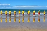 A dozen surf life savers stand looking at the ocean at Sarina. 