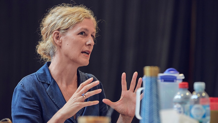 Colour close-up photo of Sarah Goodes sitting at table and talking during rehearsals for Arbus and West in 2019.