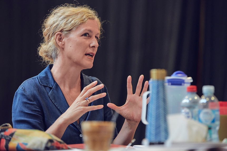 Colour close-up photo of Sarah Goodes sitting at table and talking during rehearsals for Arbus and West in 2019.