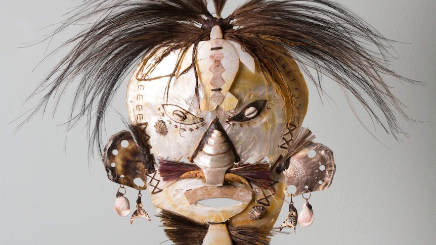 A tribal mask with brown hair strands sticking out of the top.