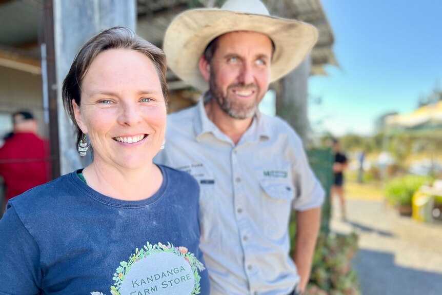 A smiling woman next to a smiling man in a large hat.