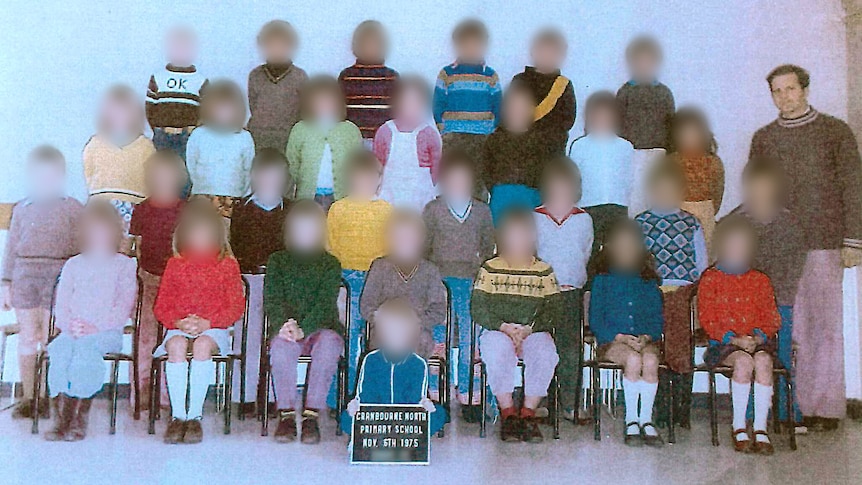 A class photo with a male teacher and the faces of all the children blurred.