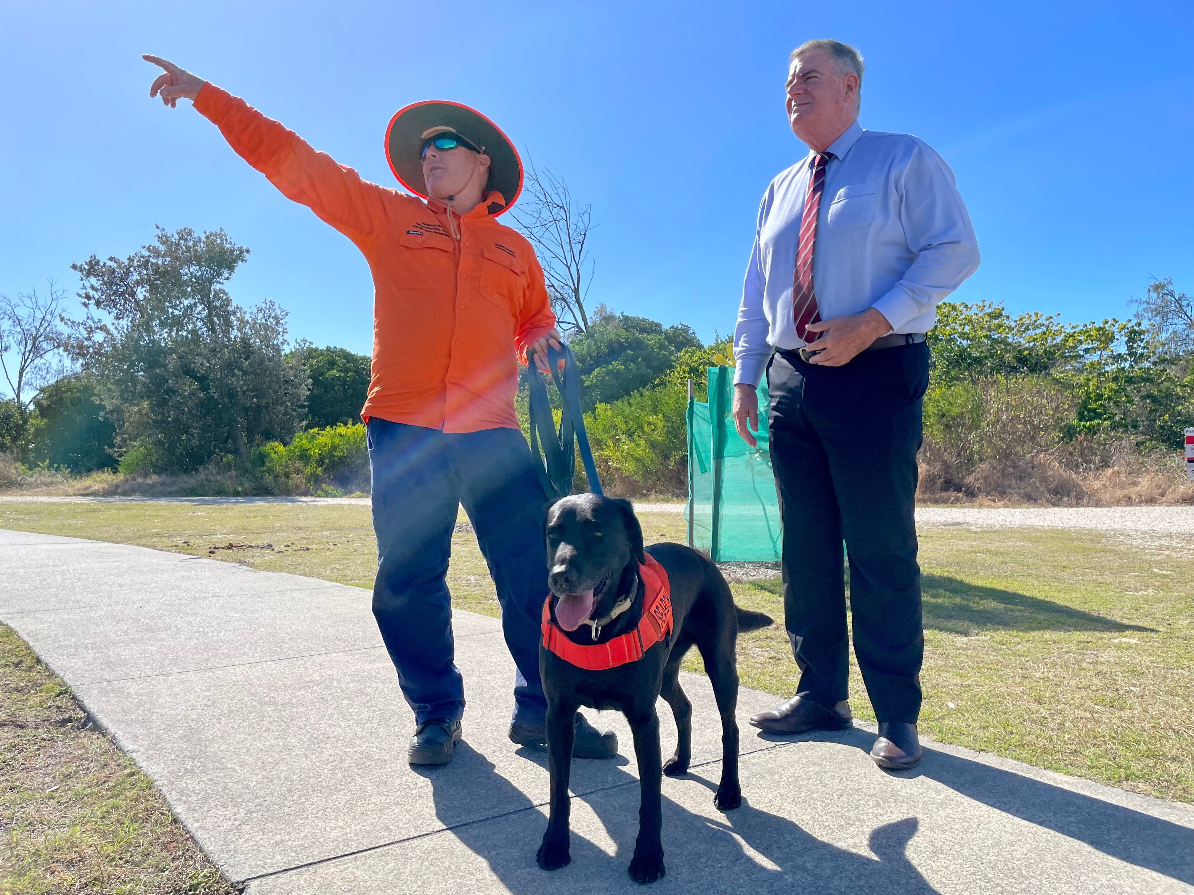 a working dog and handler standing with a government minister