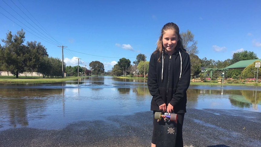 Lara Laws in her grandparents street, Wombat Street, which has been drenched in recent flooding.