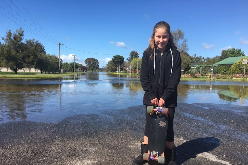 Lara Laws in her grandparents street, Wombat Street, which has been drenched in recent flooding.