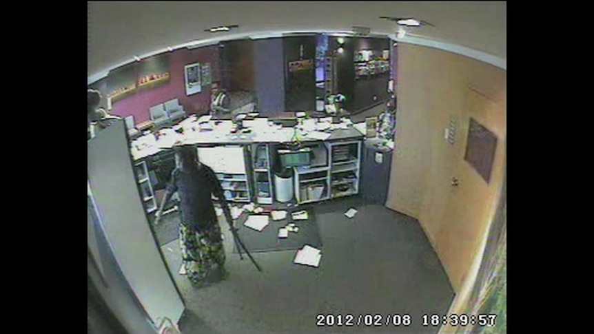CCTV image of a woman inside the hotel, holding what appears to be a leg of a camera tripod.