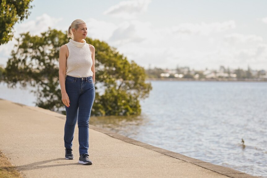 Jacqueline Goodwin walks along a path looking out at the waters of Moreton Bay at Manly.