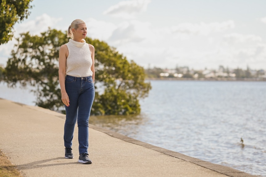 Jacqueline Goodwin walks along a path looking out at the waters of Moreton Bay at Manly.