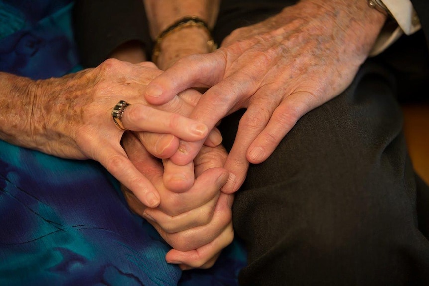 Close-up of George and Iris Barlin holding hands.