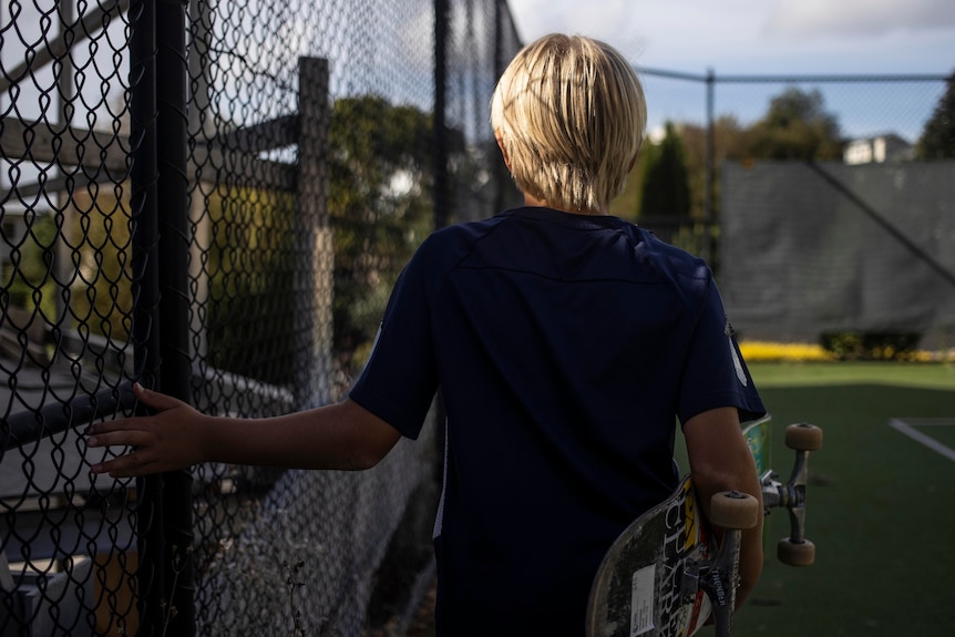 Boy running hand along fence