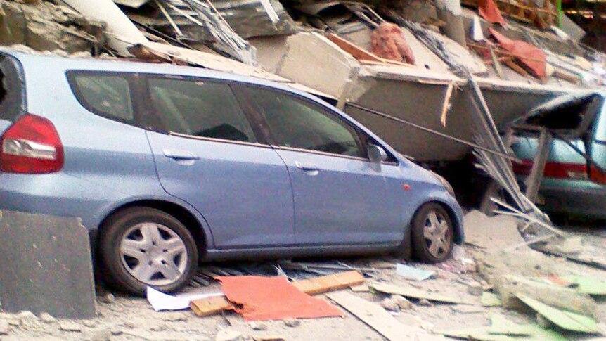 A car lies under rubble after part of a building collapsed during the earthquake.