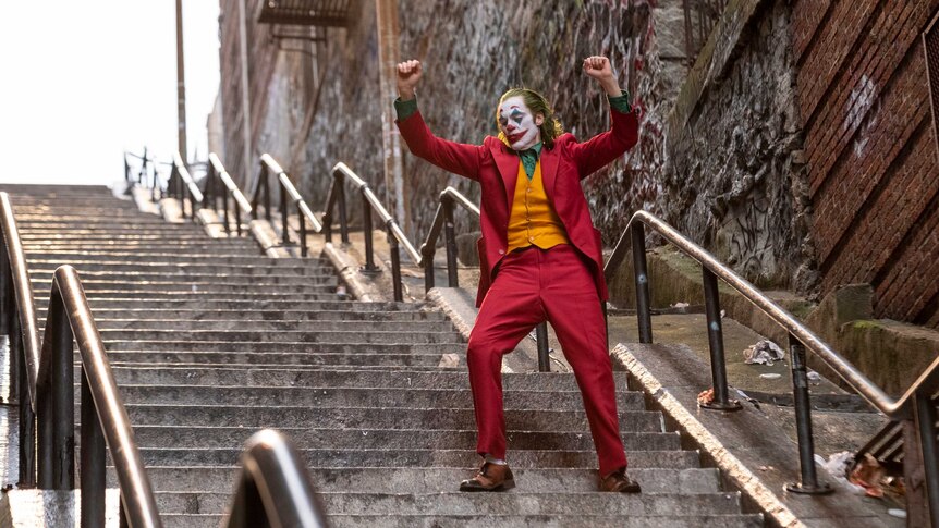 Actor Joaquin Phoenix dresses as the demented clown Joker walking down a public stairwell