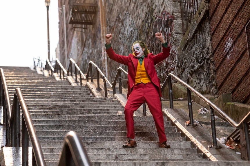 Actor Joaquin Phoenix dresses as the demented clown Joker walking down a public stairwell