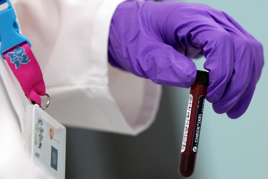 An analyst handles a vial of blood in the anti-doping laboratory in Harlow, England,