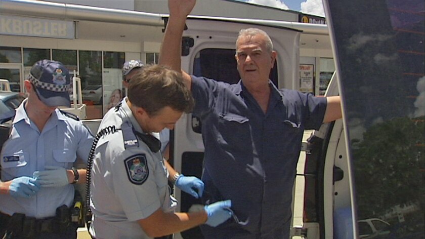 A man stands next to a police van outside former prime minister Kevin Rudd's office in Morningside.