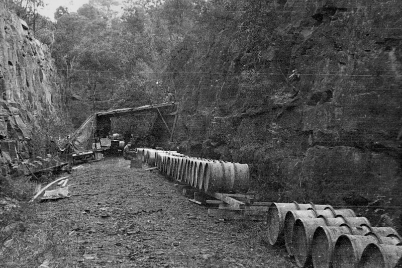 Chemical storage drums lined up outside an underground tunnel.