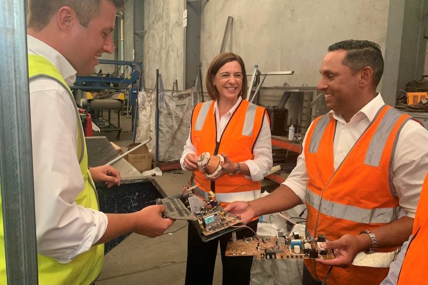 Woman and two men in high-vis vests holding e-waste