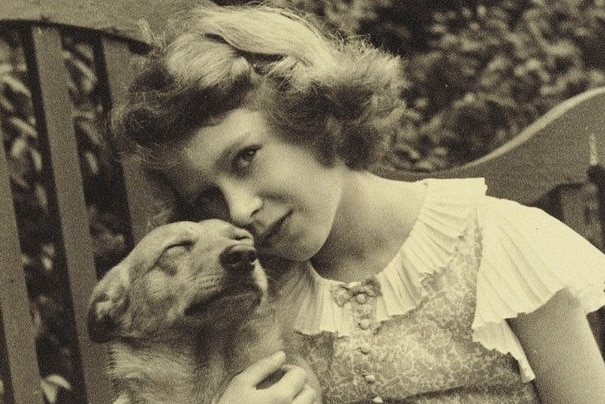 A black and white photograph of Princess Elizabeth cuddling a small dog.