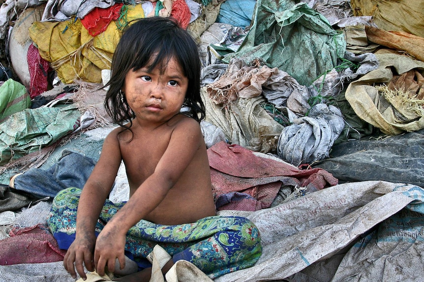 Young girl sits at a Cambodian rubbish dump in Siem Reap