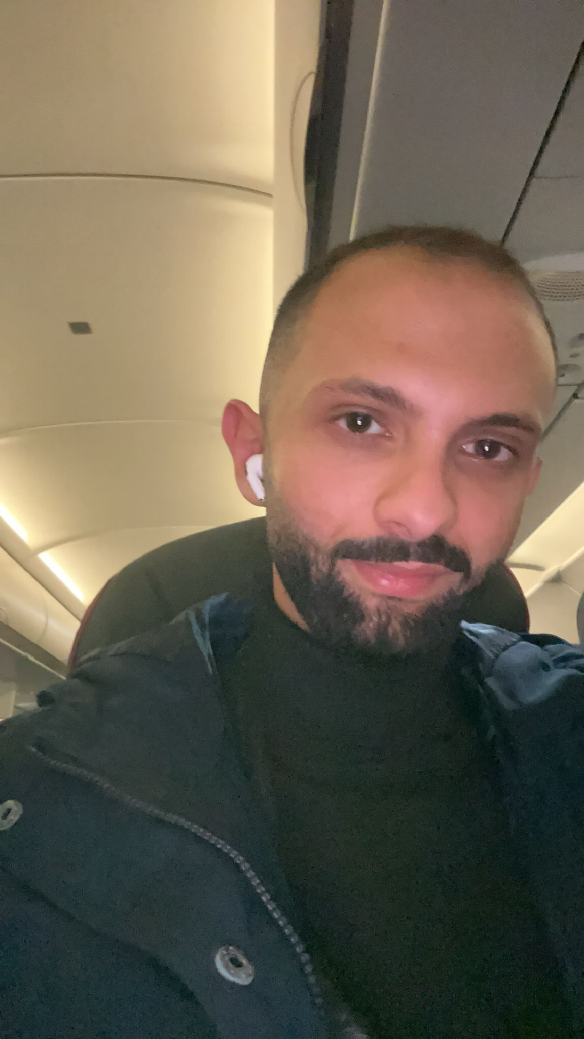 Hani sitting listening to headphoens on the plane. 