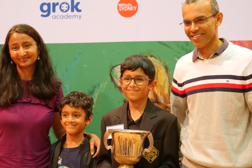 A young boy holding a trophy with his family