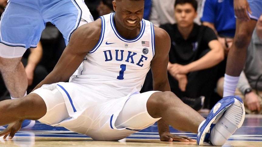 Zion Williamson grimaces as he does the splits, with his left trainer split open