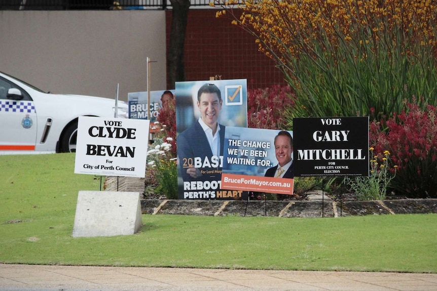 Campaign posters for vacancies on Perth's city council inside the median of a busy roundabout