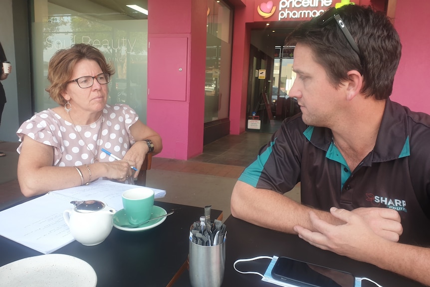 A woman talks to a man over coffee.