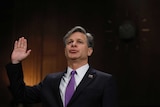 Christopher Wray raises his hand as he is sworn in prior to testifying.