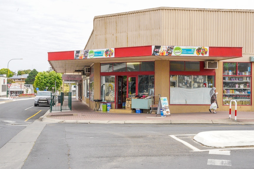 A red painted shop front with stalls outside stands out on a street corner.