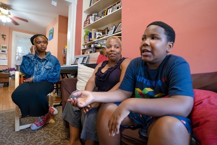 A mum and her two teenaged children talk on the couch