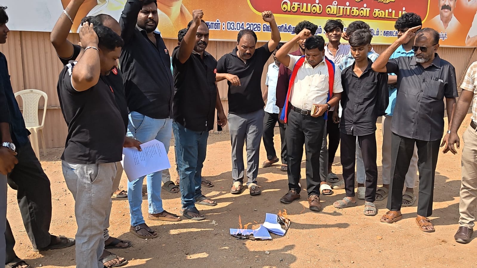 A group of men in Tiruppur, Tamil Nadu, India look at a burning piece of paper on the ground