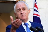 Prime Minister Malcolm Turnbull holds out his hand while speaking at a press conference outside Parliament House.