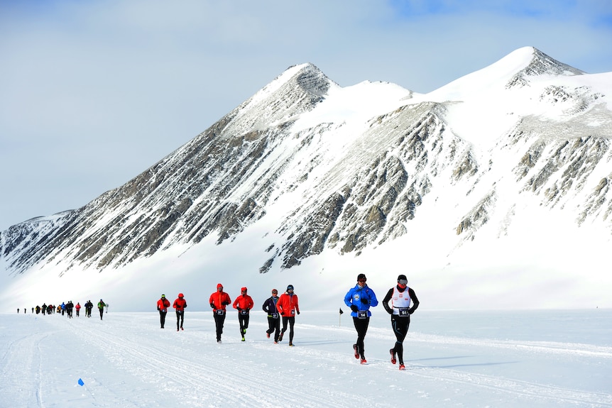 Runners run along ice and snow in Antarctica. 